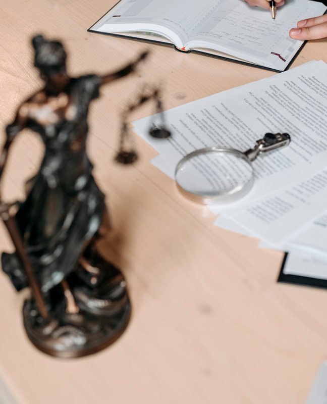 Abogada escribiendo en agenda con estatua de la justicia en la mesa
